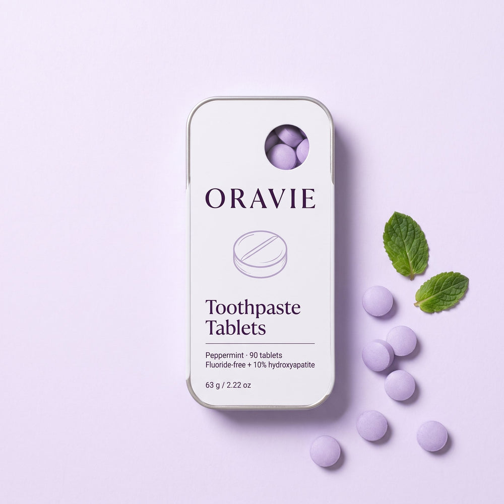 ORAVIE Toothpaste Tablets tin on lavender paper with loose tablets and fresh mint leaves